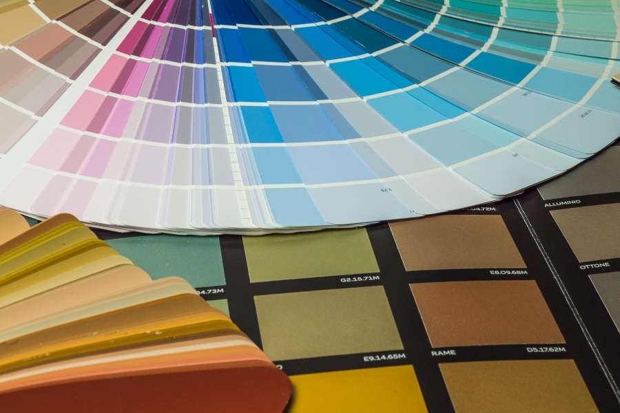 A fanned paint swatch book displaying hundreds of shades alongside material sample cards to help choose the right color palette for a home.