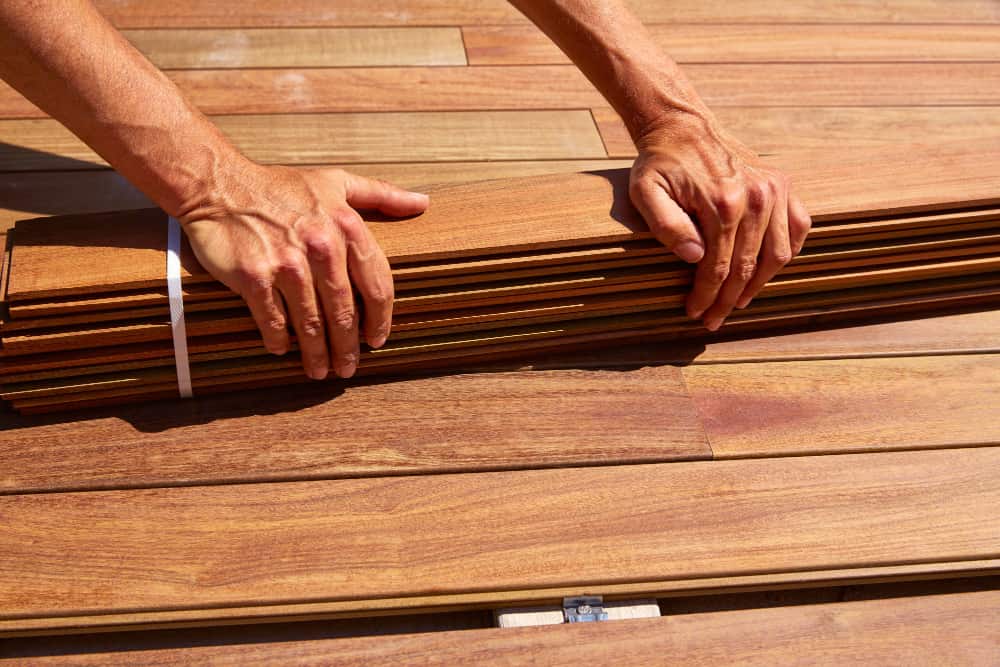 Close-up of a contractor holding premium hardwood boards while deciding which wood is best for decking for a new outdoor project