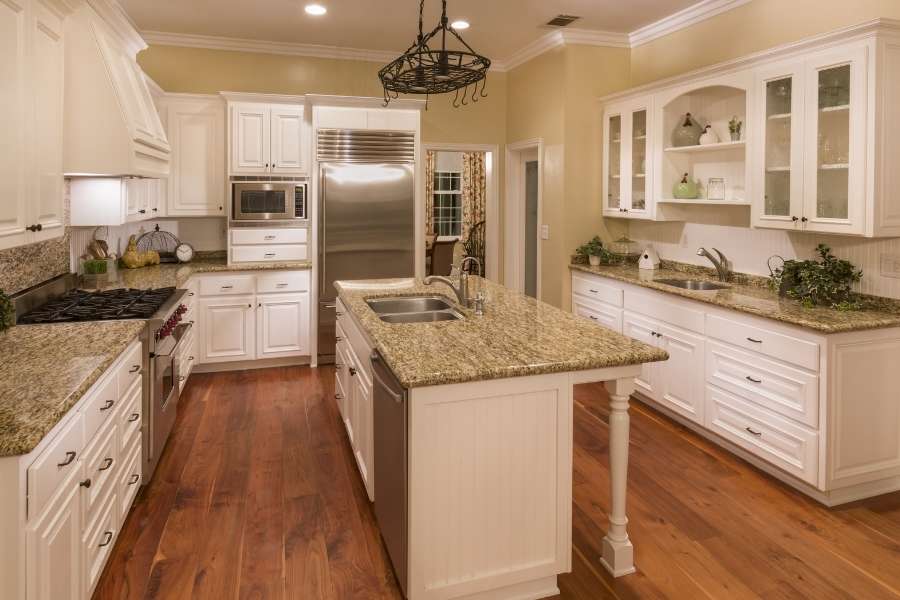 A spacious kitchen featuring custom furniture projects including white cabinetry and a central island.